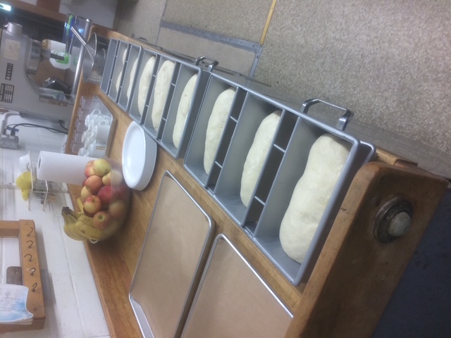Rows of bread loaves proofing in a camp kitchen