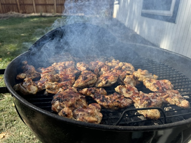 Chicken grilling over charcoal with smoke rising