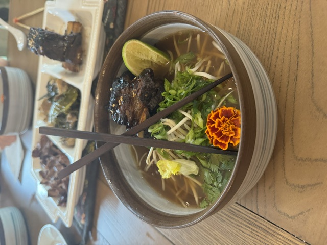 Short rib pho bowl garnished with herbs and marigold