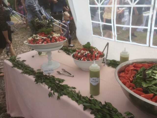 Wedding buffet table under a tent with salads and garlands
